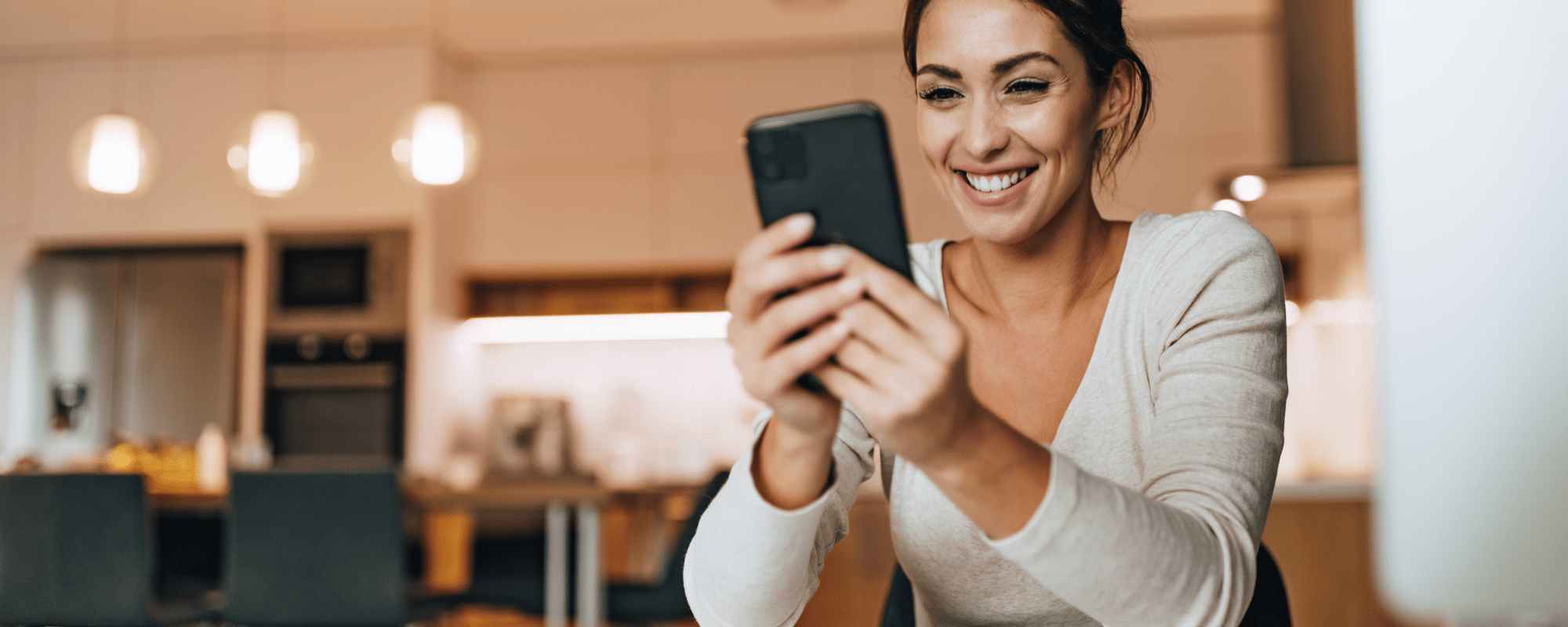 Woman in cafe stitting at table looking at phone. 