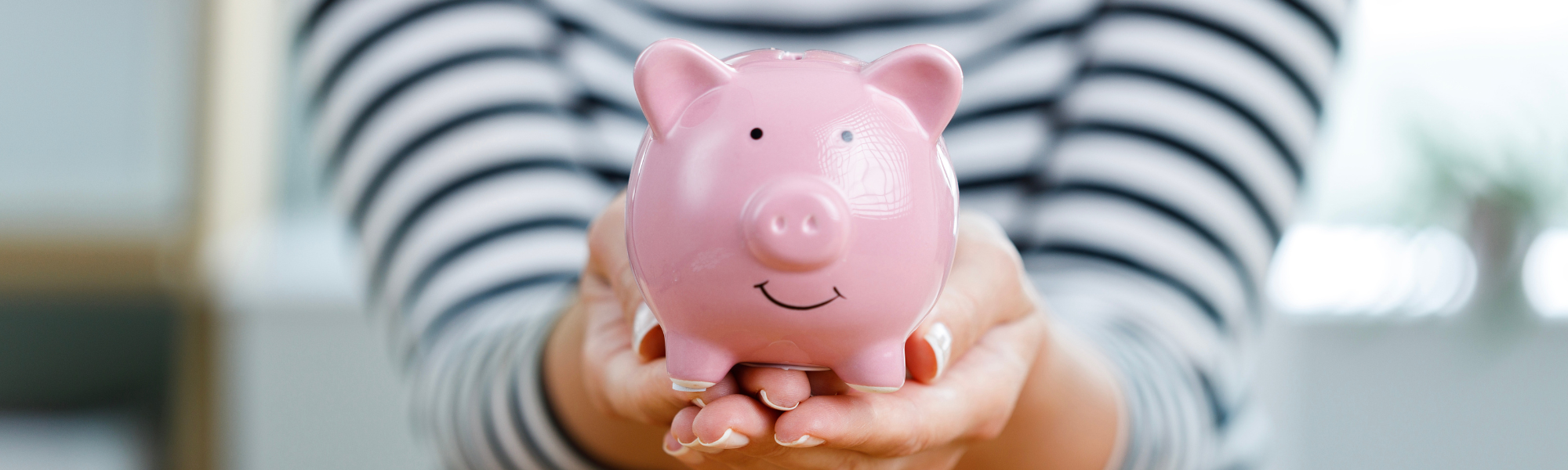 Person holding pink china piggy bank in both hands